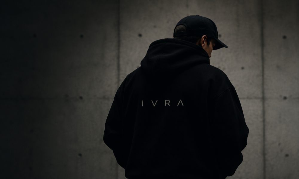 Person wearing a black hoodie with 'IVRA' logo against a dark background